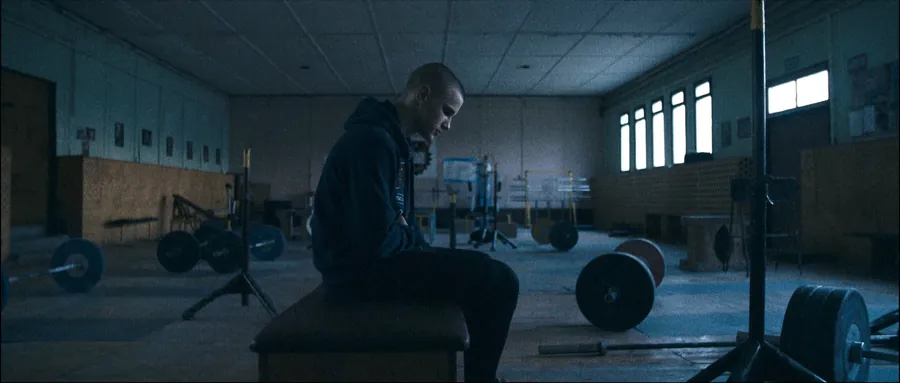 The boxer sitting alone on a bench in an empty gym